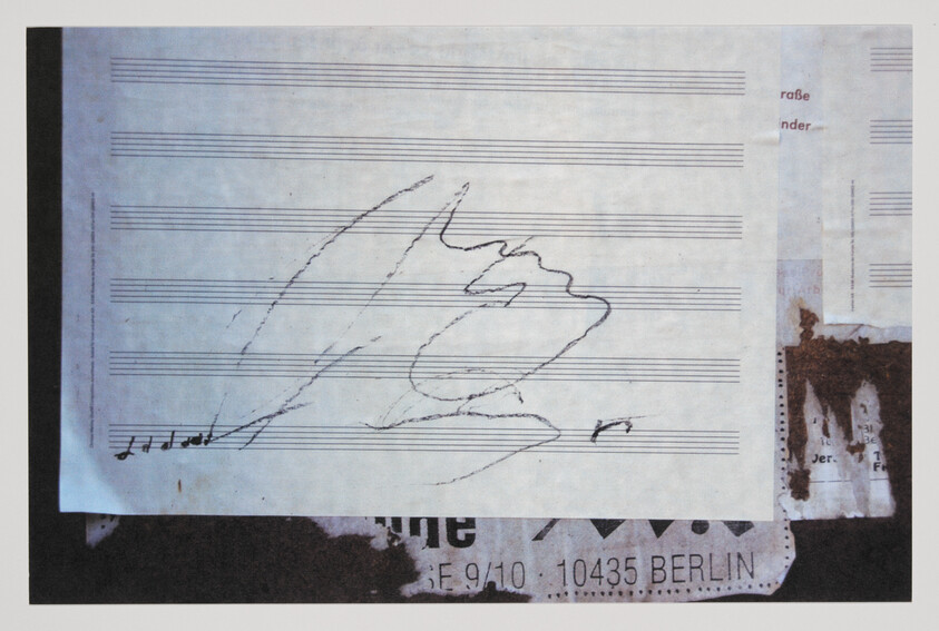 A mixed media artwork featuring a piece of sheet music with a few musical notes and a rough sketch of a profile of a face drawn across the staves. The background includes various overlaid textures and elements, including a partial address label with the text "10435 BERLIN" and other obscured text, suggesting a collage technique.