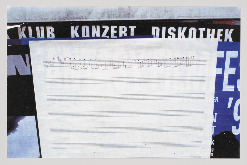 A large sheet of blank staff paper with a short handwritten musical notation at the top.