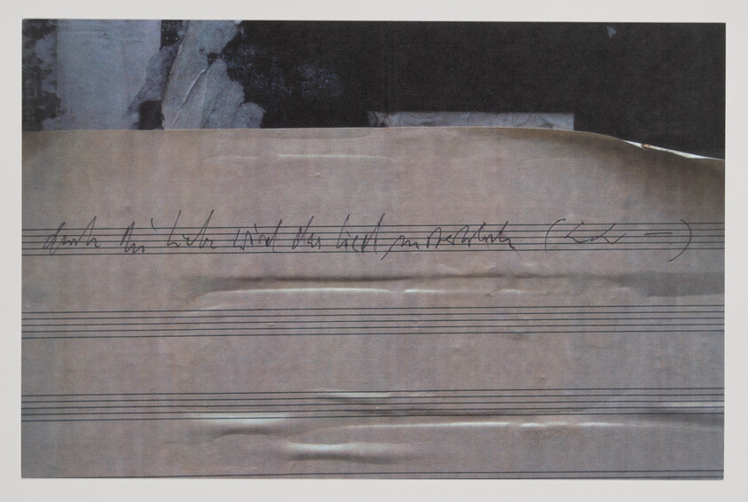 Sheet music paper with handwritten cursive notes and empty staff lines across the page.