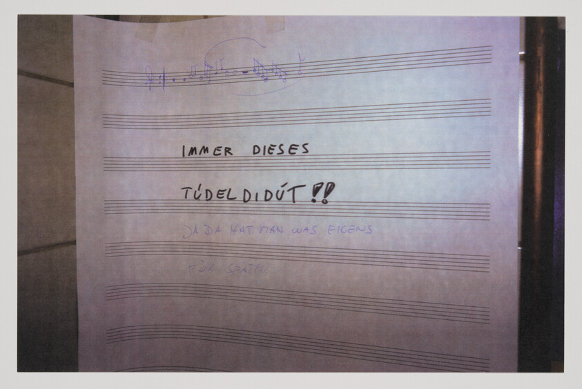 Large sheet music paper on a wall with handwritten text "Immer dieses" and "Tüdel didüt!".