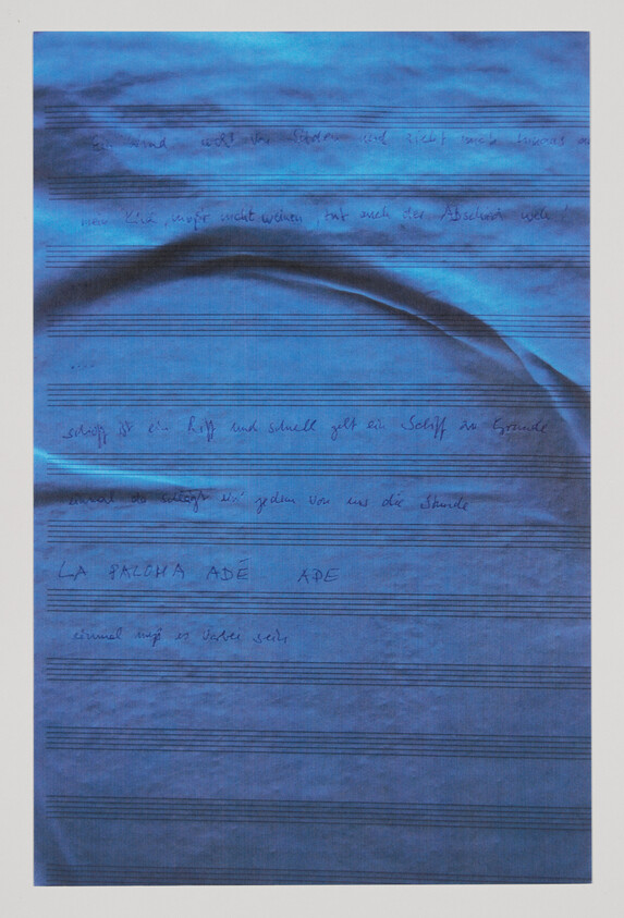 Blue sheet with faint handwritten notes and musical staff lines, showing a curved fold near the top.