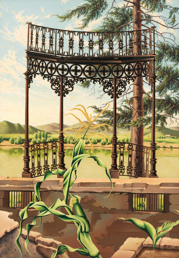 Ornate two-level wrought-iron balcony stands above a broken stone wall with corn plants.