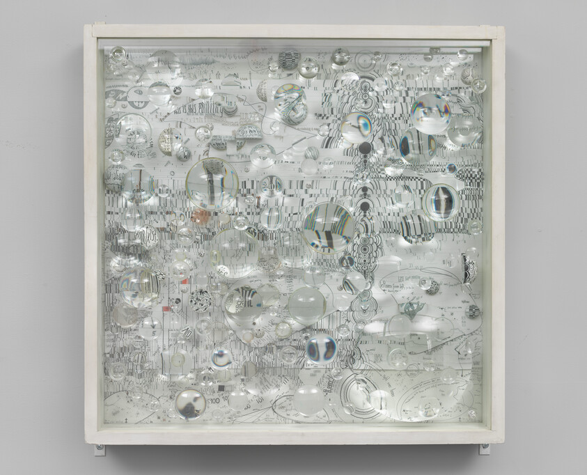 A framed artwork with numerous clear glass lenses distorting a black-and-white patterned drawing beneath.