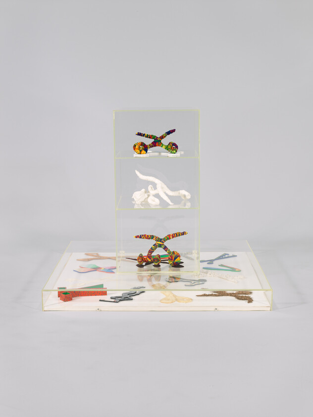 A clear three-tiered display holding colorful twisted sculptures and various flattened cutouts on the base.