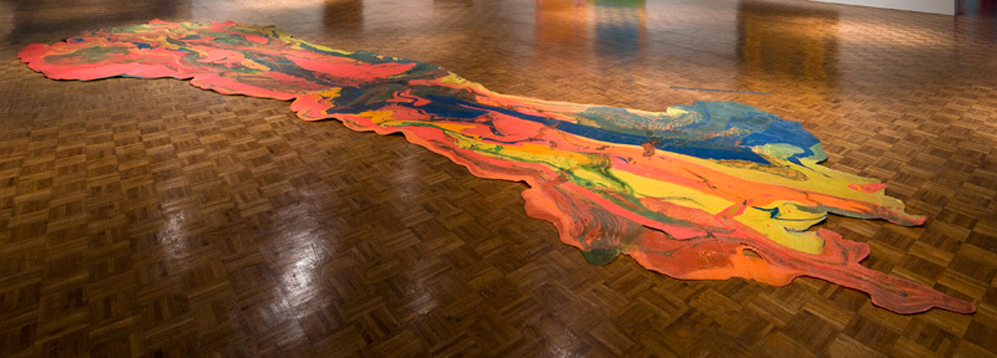 A large irregularly shaped "spill" made of flowing and pooling red, blue, green, orange, and yellow.