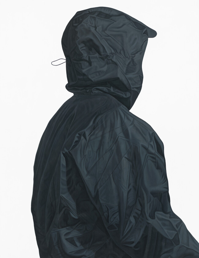 A person turned away wearing a dark hooded rain jacket with the hood up.