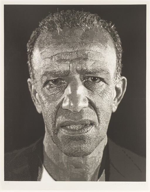 Close-up portrait of an older man with a serious expression and deeply textured skin.