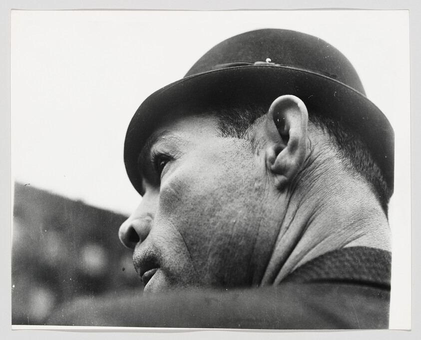 Close-up of a man in a bowler hat looking upward and to the left.