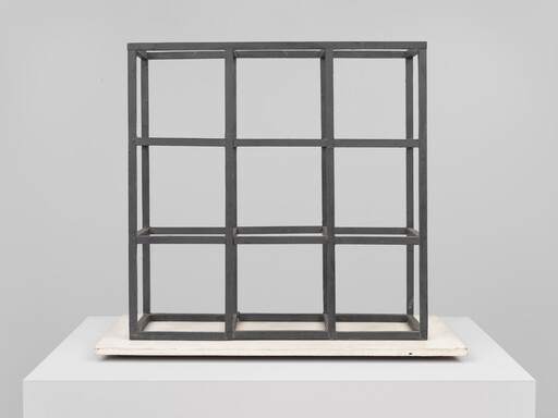 A black metal three-by-three grid sculpture displayed on a white plinth.