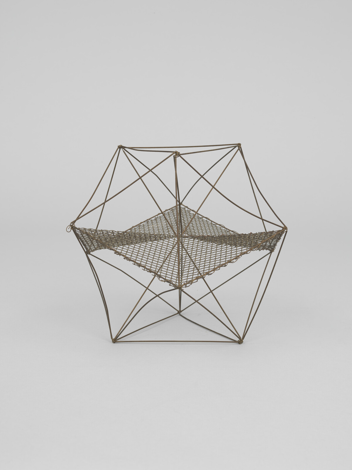 Wireframe geometric sculpture with a square woven mesh suspended inside a hexagonal metal frame.