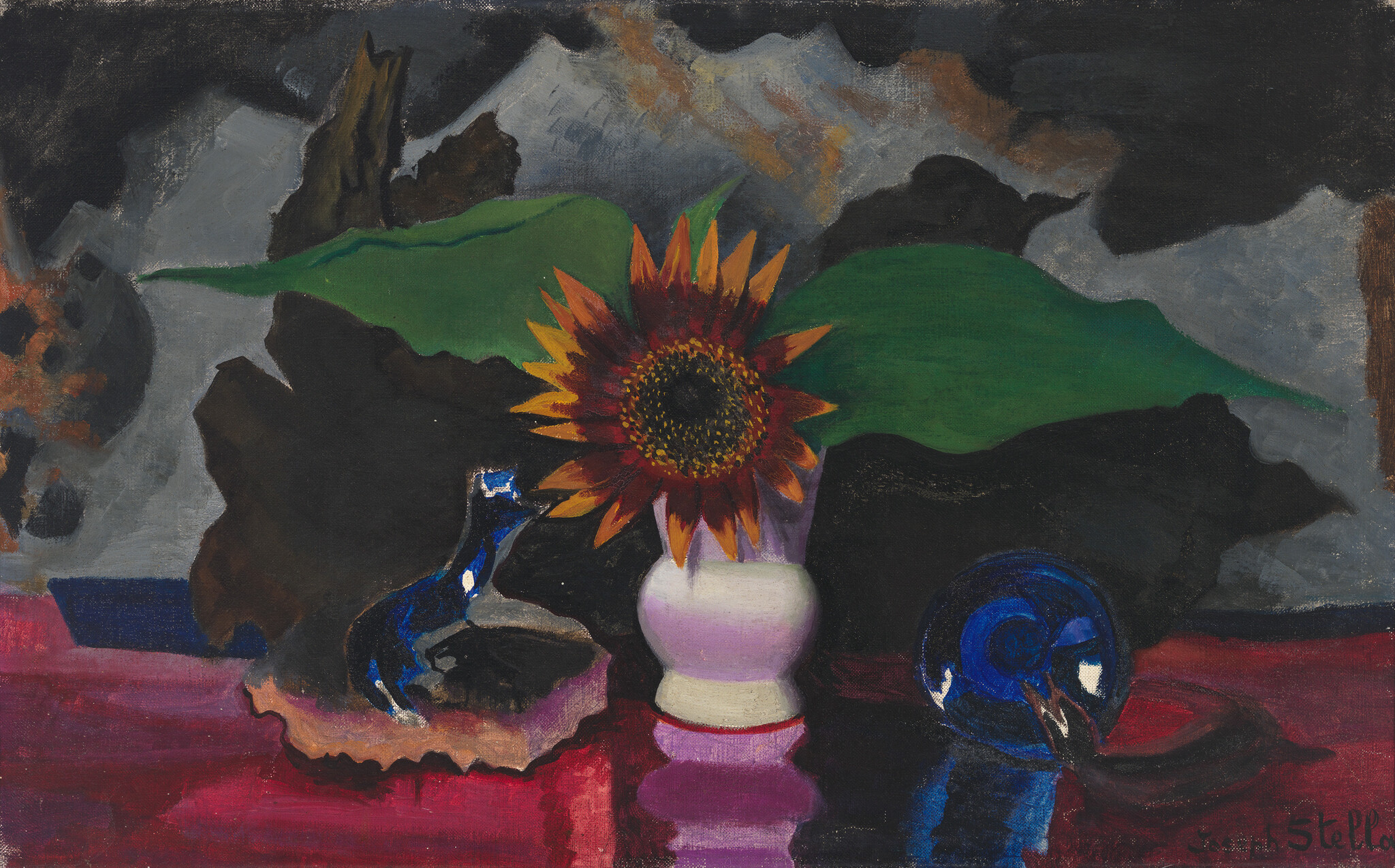 A sunflower in a small white vase sits between blue glass objects on a red table.