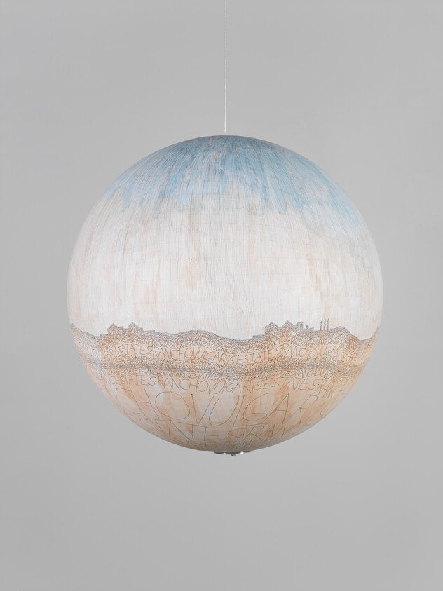 A large hanging spherical lamp painted pale blue and beige with handwritten text around its middle.