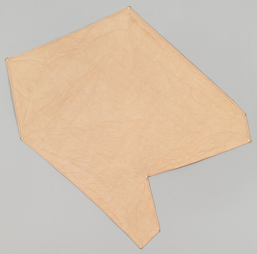 Large peach-colored irregular fabric sheet pinned at multiple corners against a gray surface.