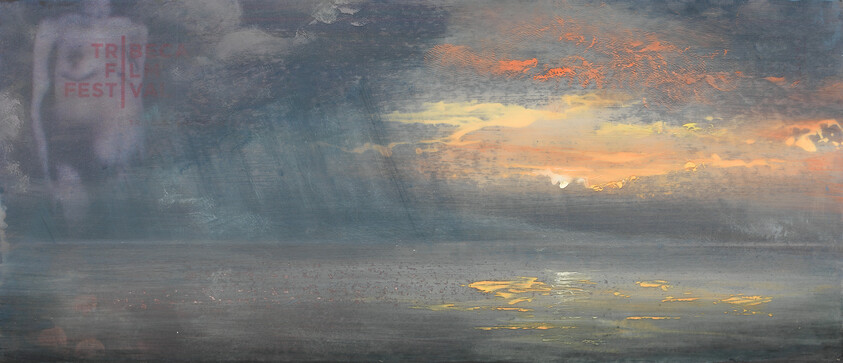 A calm sea under heavy clouds with a glowing sunset breaking through and light reflecting on the water.