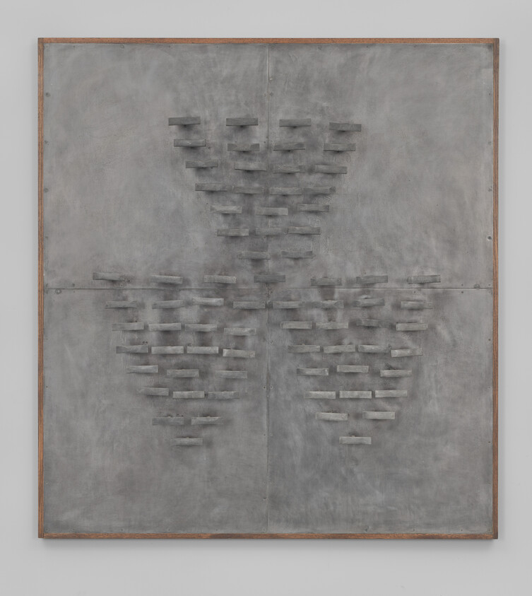 Large gray metal panel with three triangular clusters of small rectangular protruding blocks.