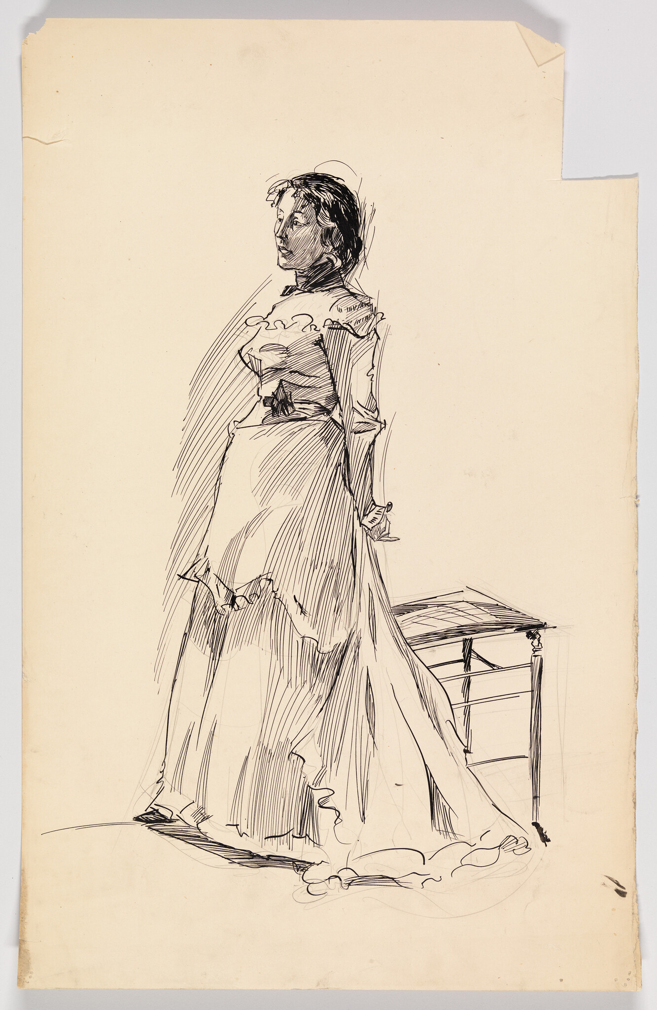 A woman in a long dress stands beside a small table, looking slightly upward.