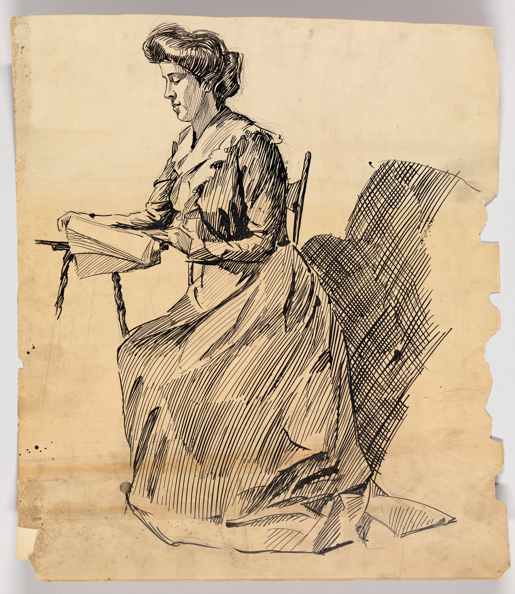 A seated woman in a long dress reading a book at a small table.