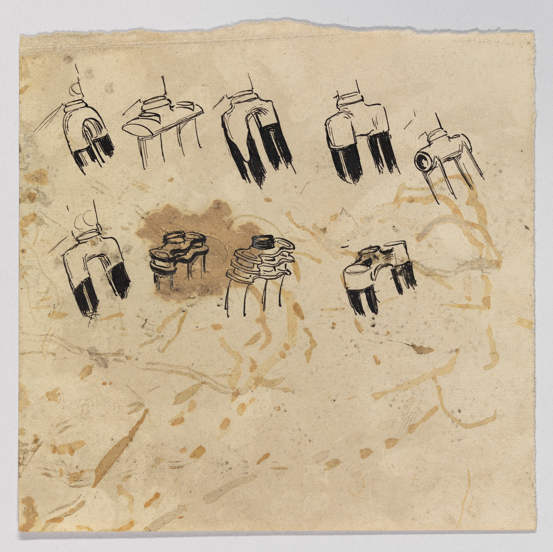 Several ink sketches of small three-pronged mechanical connectors or plug-like parts on stained paper.