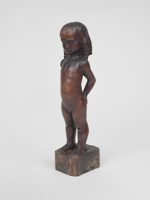 Wooden sculpture of a standing nude child with hands behind their back on a base.