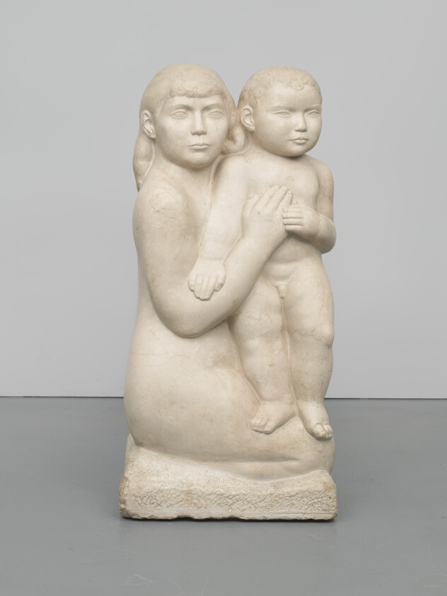 A stone sculpture of a seated woman holding a standing child against her chest.