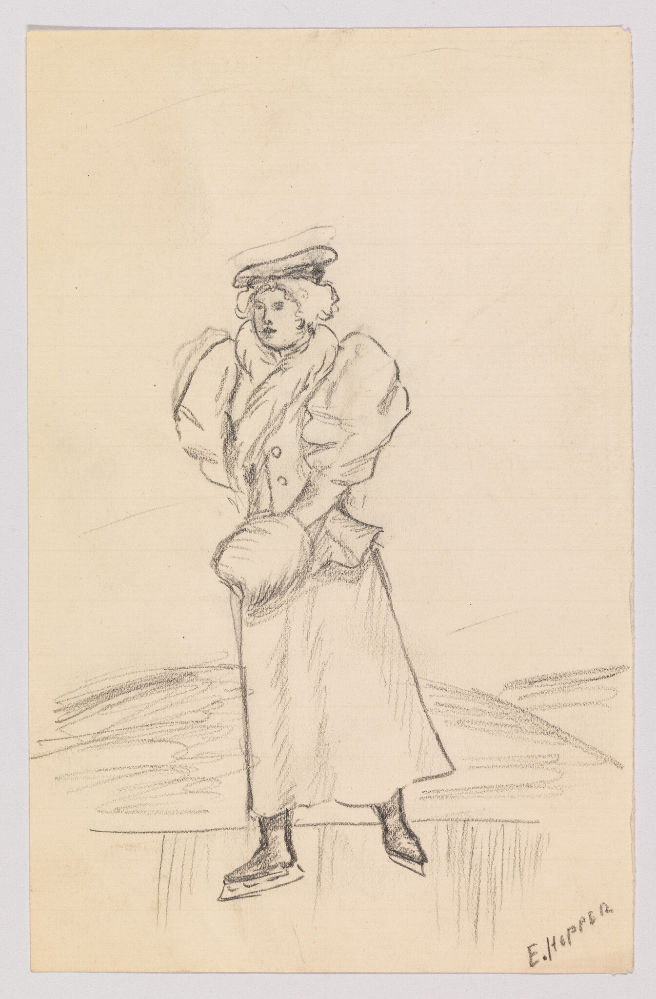 A woman in a long coat and muff stands on ice wearing skating boots.