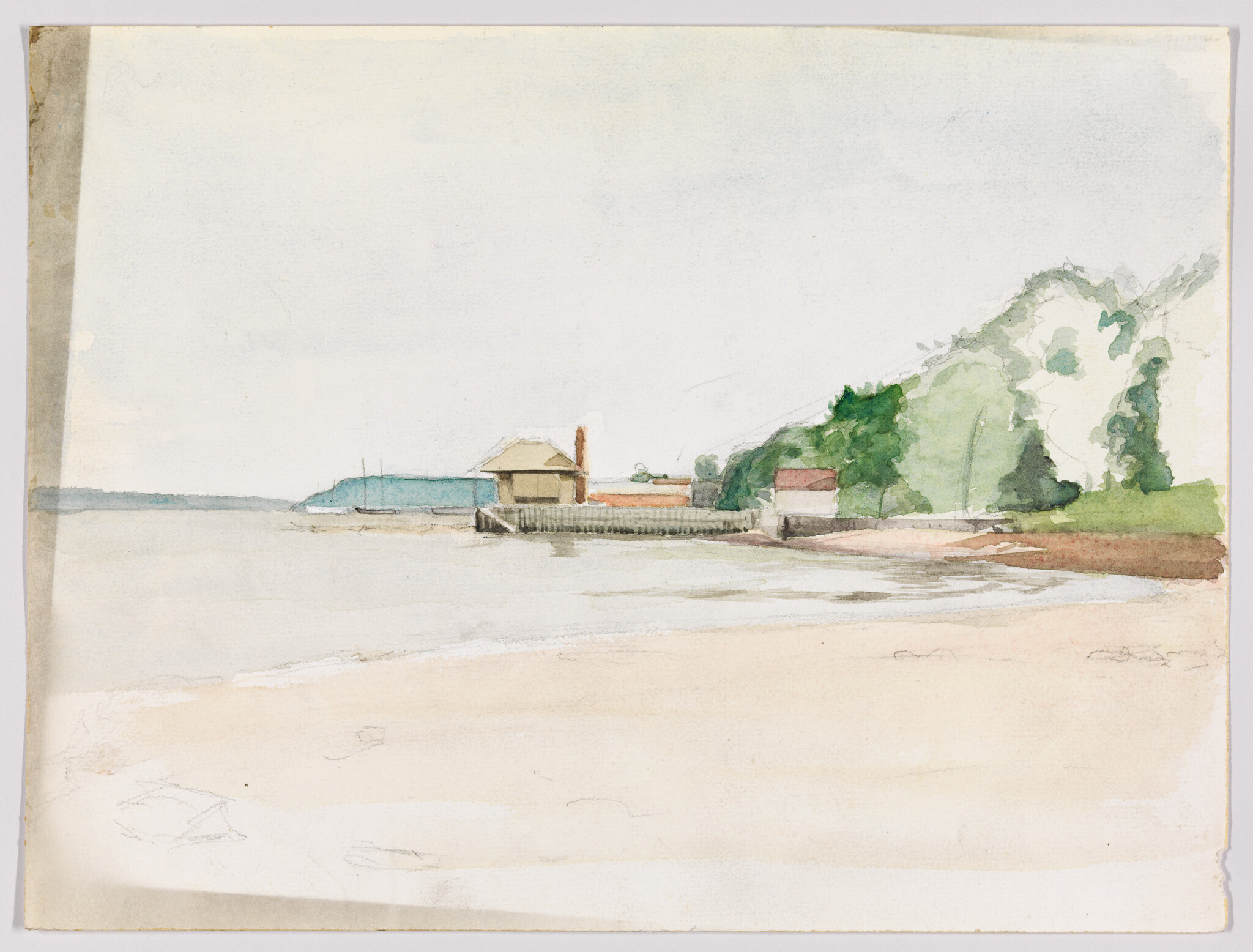 A calm sandy beach with a small pier, boathouse, and green tree-covered hill.