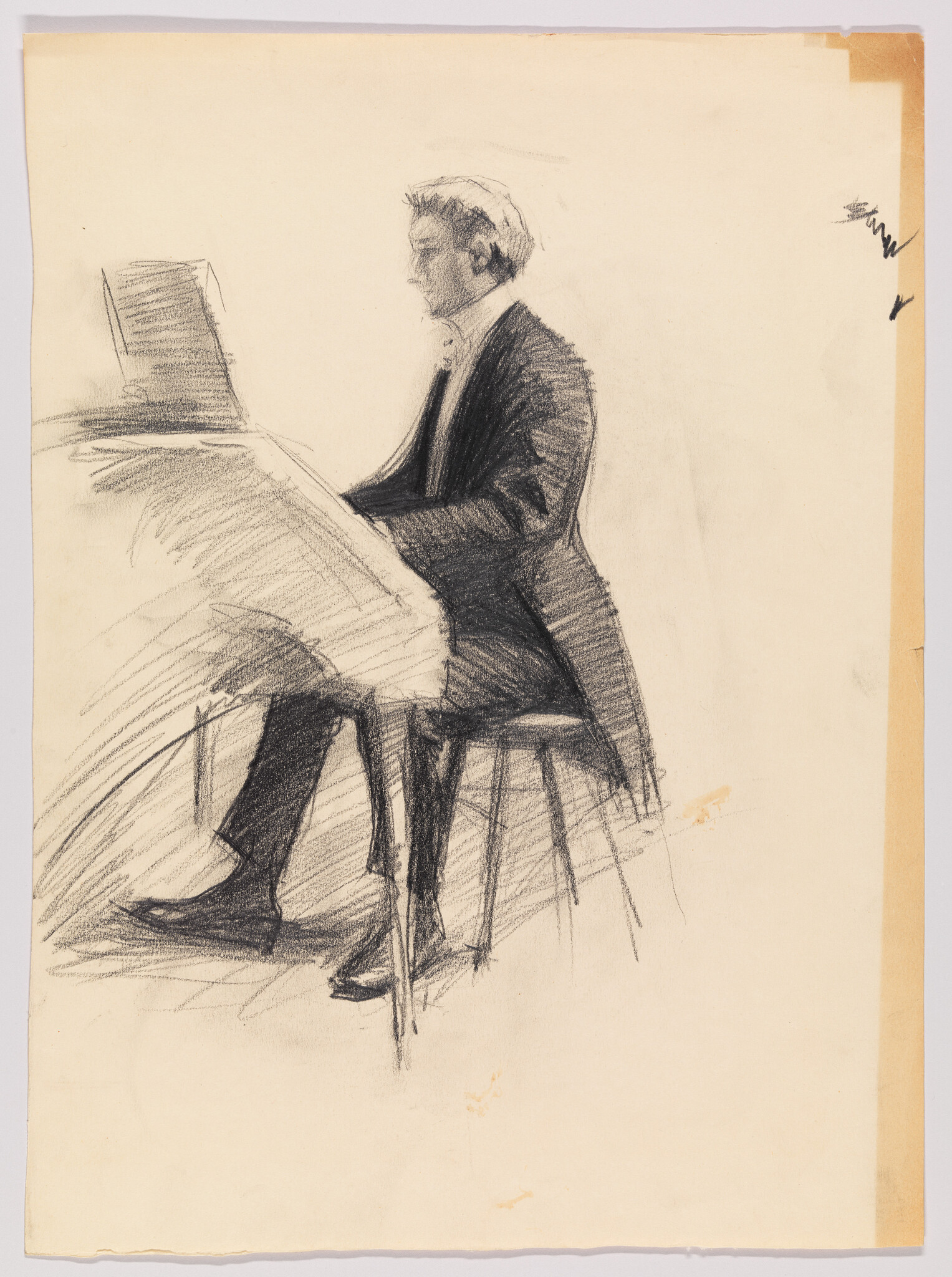 A man in formal attire sits at a piano, playing from sheet music.
