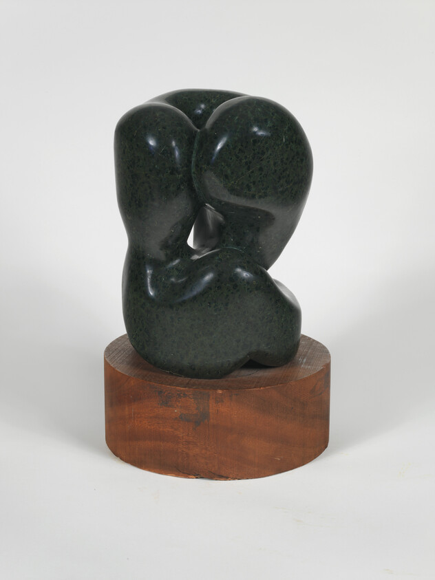 Dark green abstract stone sculpture with rounded forms resting on a circular wooden base.