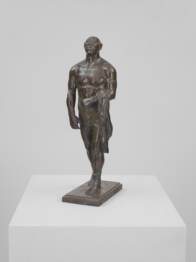 Bronze sculpture of a standing male figure walking forward with draped cloth over one arm.