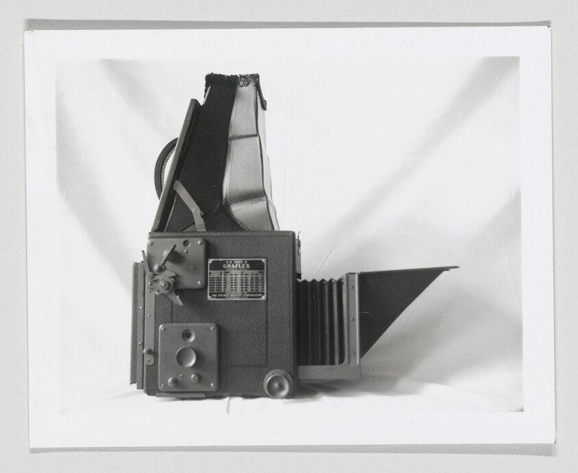 Large vintage Graflex bellows camera with folded viewfinder and extended focusing hood.