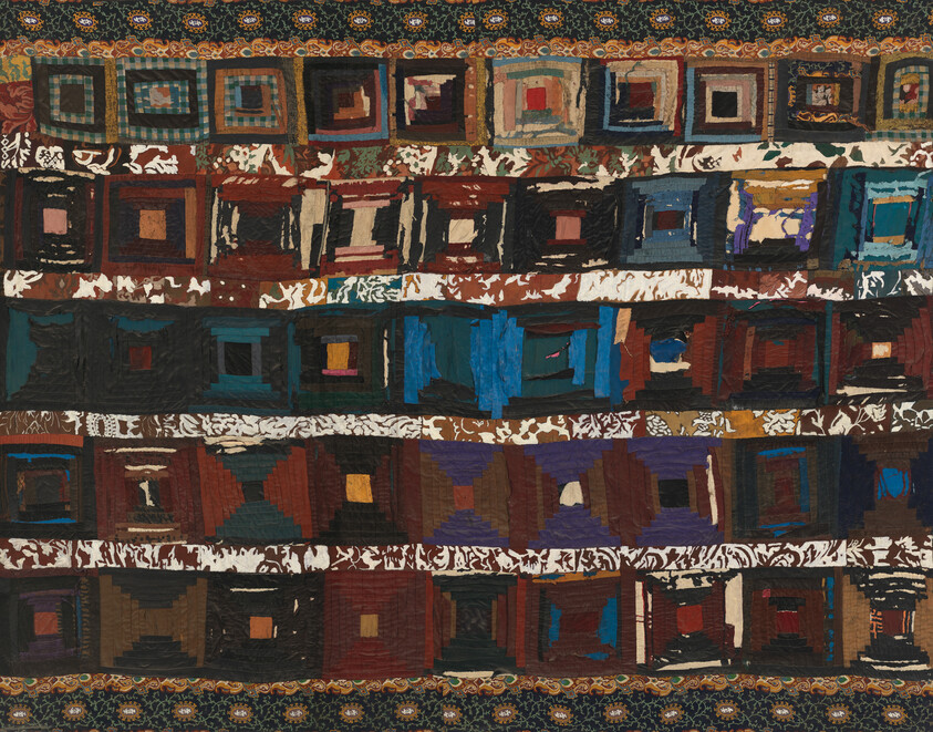 A handmade quilt with horizontal rows of multicolored square log-cabin blocks and patterned sashing.