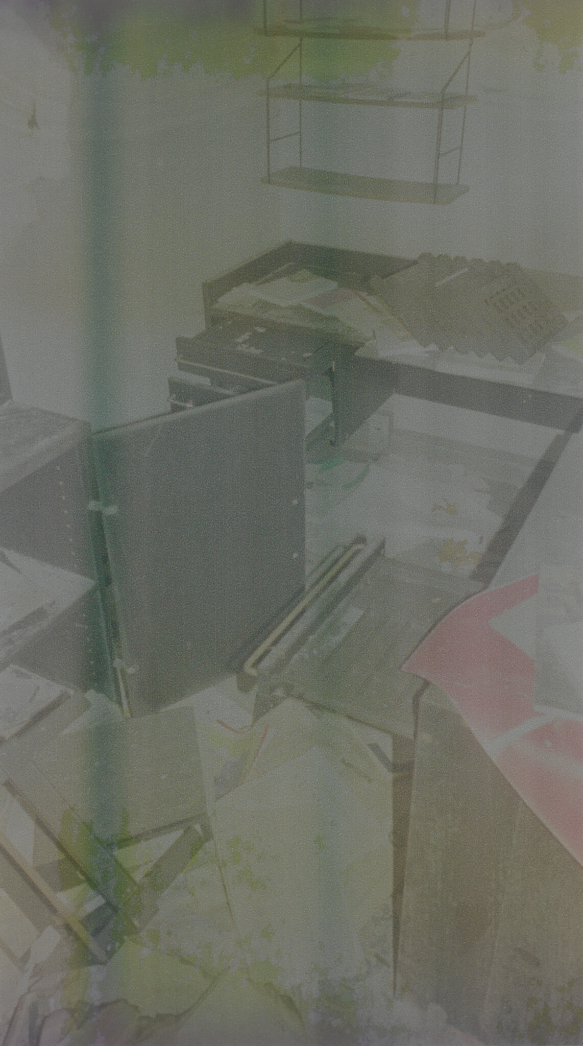 Several overturned desks, scattered papers, and a hanging shelf clutter a small room.