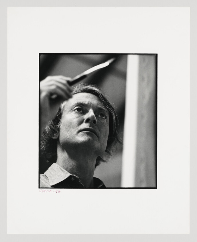A black and white photograph of a contemplative man looking upward, with his hand partially visible as it brushes through his hair. The photo is framed with a white border, and there is a signature and the year '1980' written at the bottom.