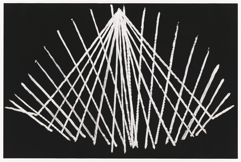 White sticks arranged in a radiating, crisscross pattern forming a triangular fan on black.
