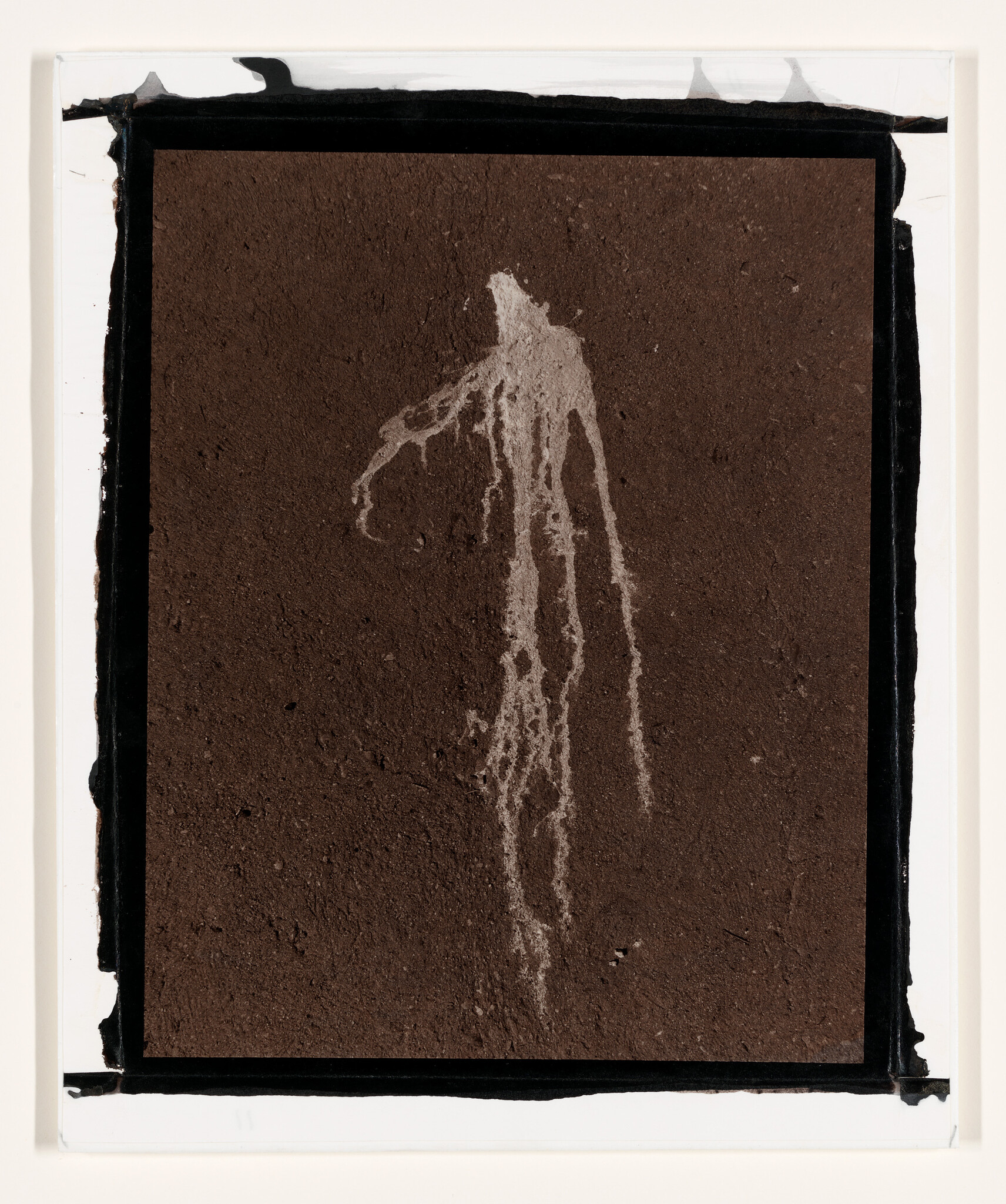 A pale drip stain on a dark textured surface resembling a tall, ghostlike figure.