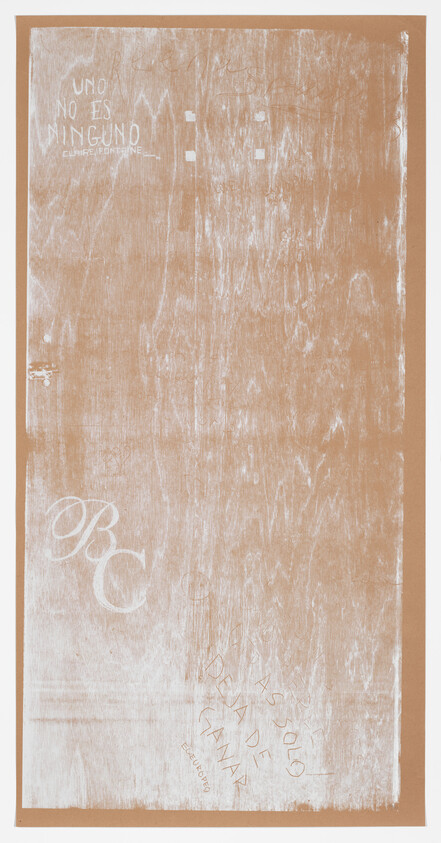 A wooden surface with faded white graffiti, including the phrases "UNO NO ES NINGUNO" and "BC" written on it.