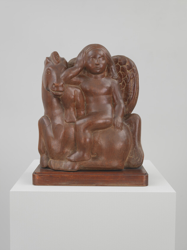 A wooden sculpture of a winged child sitting on a horse with hand raised to head.