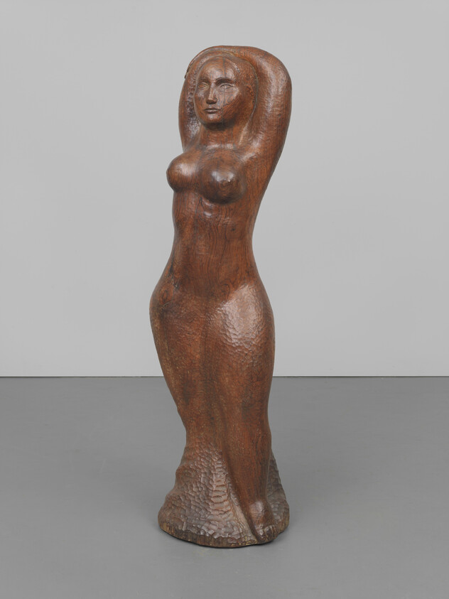 Carved wooden sculpture of a standing nude woman with her arms raised behind her head.