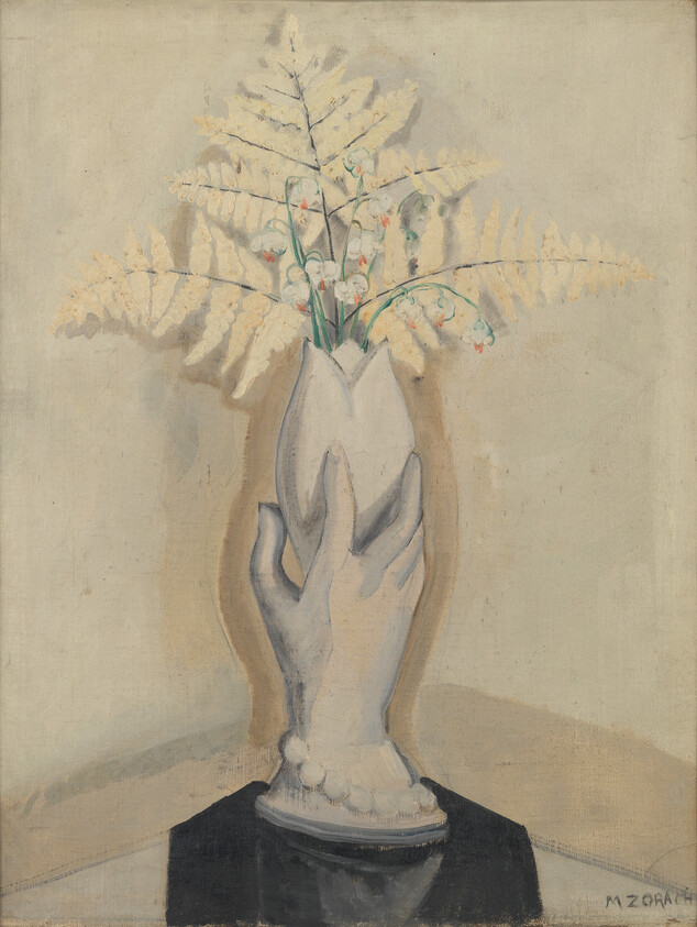 A sculpted hand-shaped vase holds delicate white lily-of-the-valley blooms and pale fern fronds.