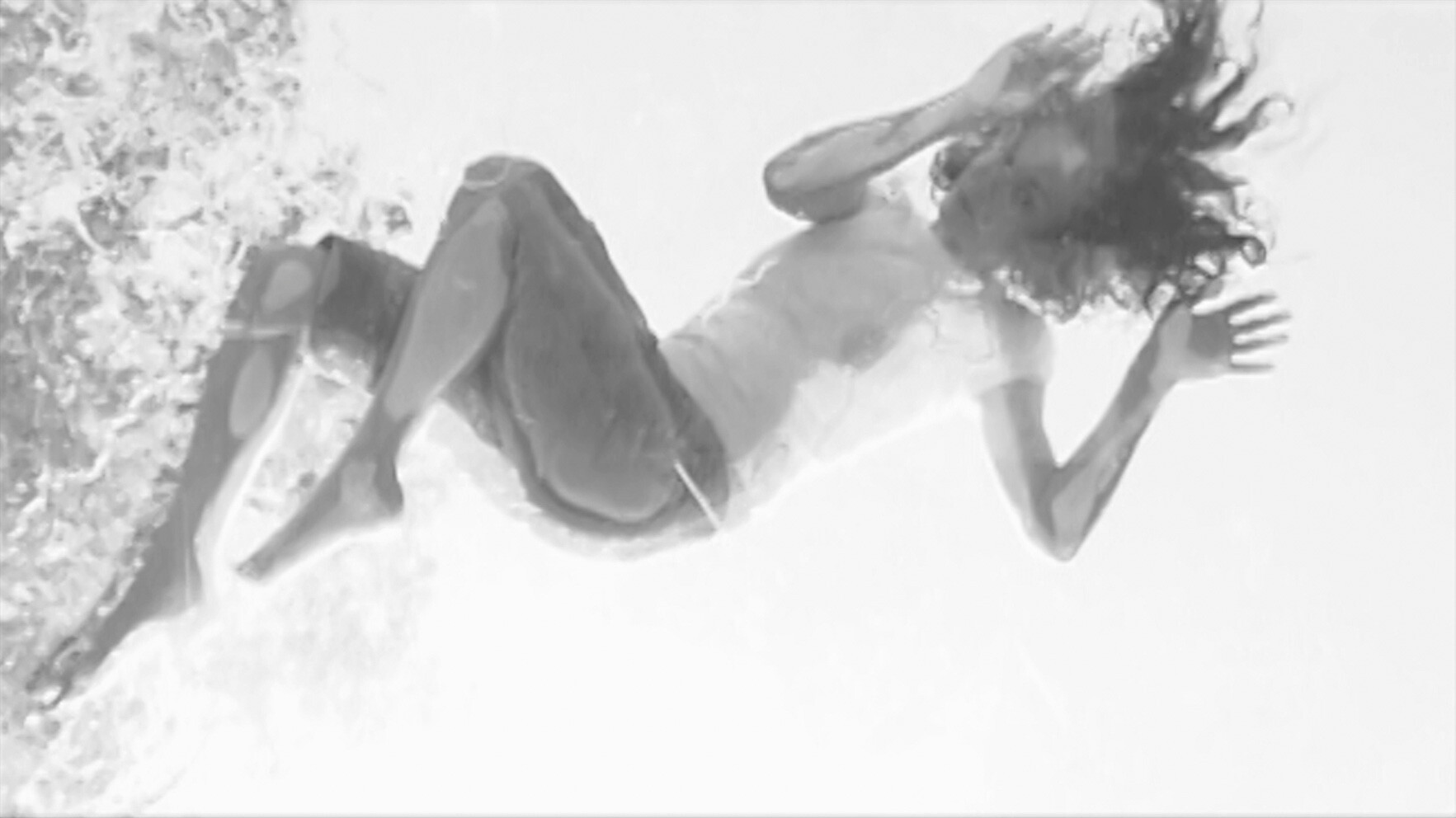 Person falling backward into shallow water with hair flipping and legs bent.