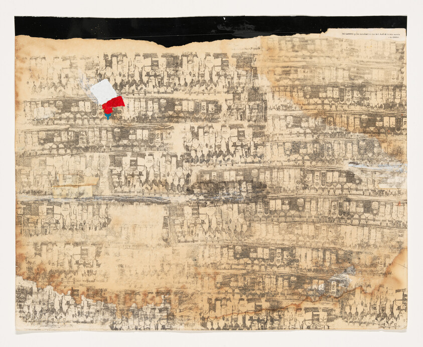 An aged and weathered piece of paper with a repetitive, densely packed cityscape print. The print appears faded and is overlaid with smudges and discoloration. A torn piece of paper with a red and blue mark is affixed near the top center. The top edge of the paper is covered with a black strip, and there's text on the upper right corner that is mostly illegible due to damage.