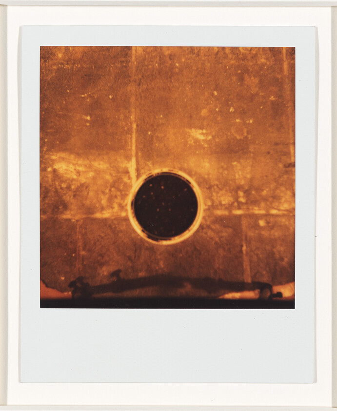 A dark circular drain set in worn orange-brown tiled floor, viewed from above.