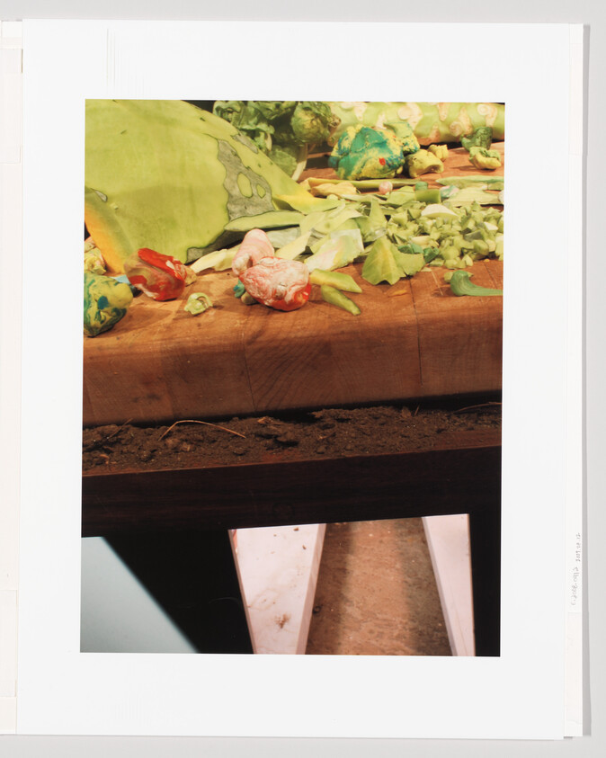 A wooden cutting board scattered with chopped leafy greens and small colorful vegetable pieces.