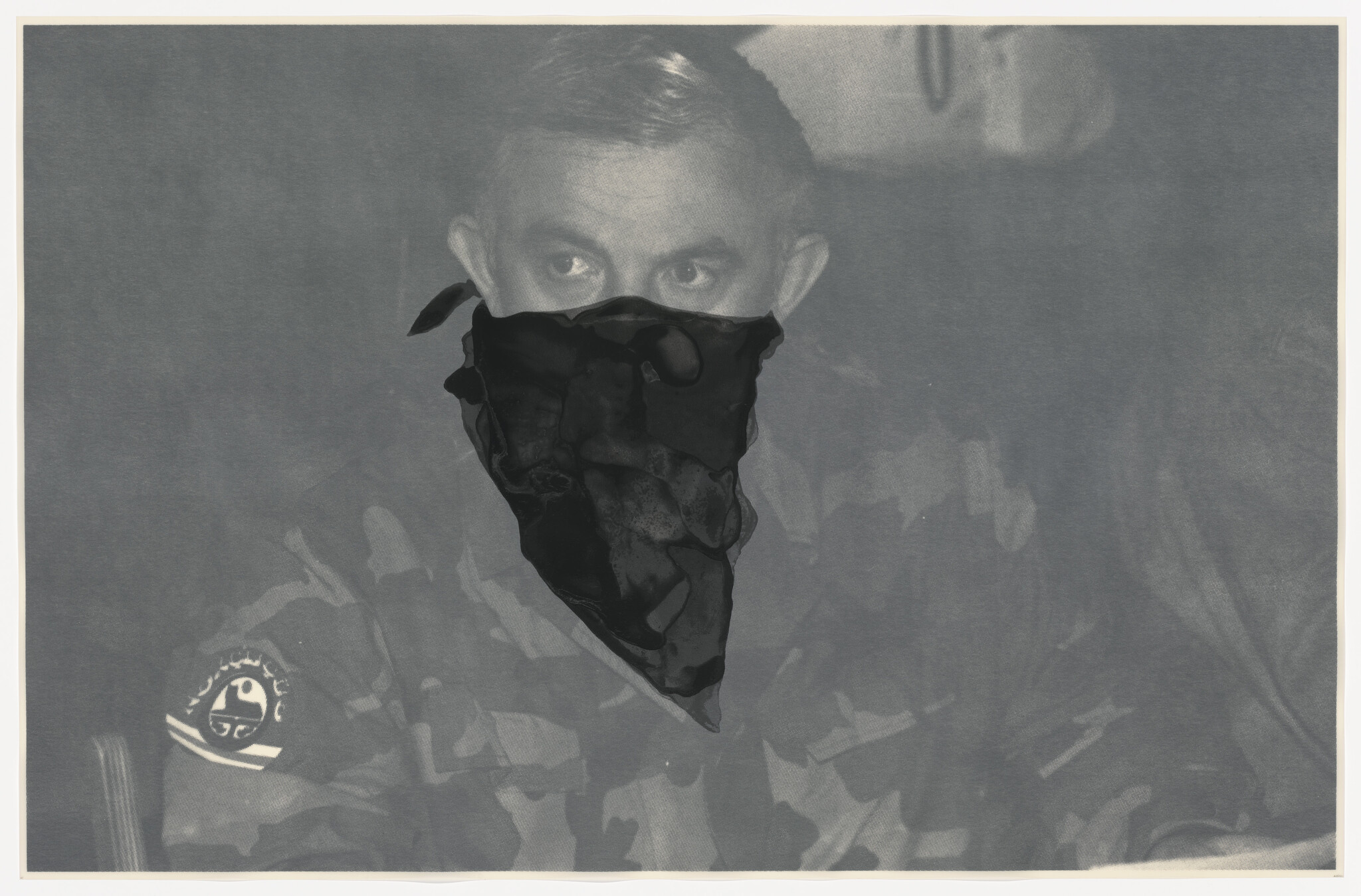 Man in camouflage uniform wearing a dark bandana over his lower face and looking sideways.