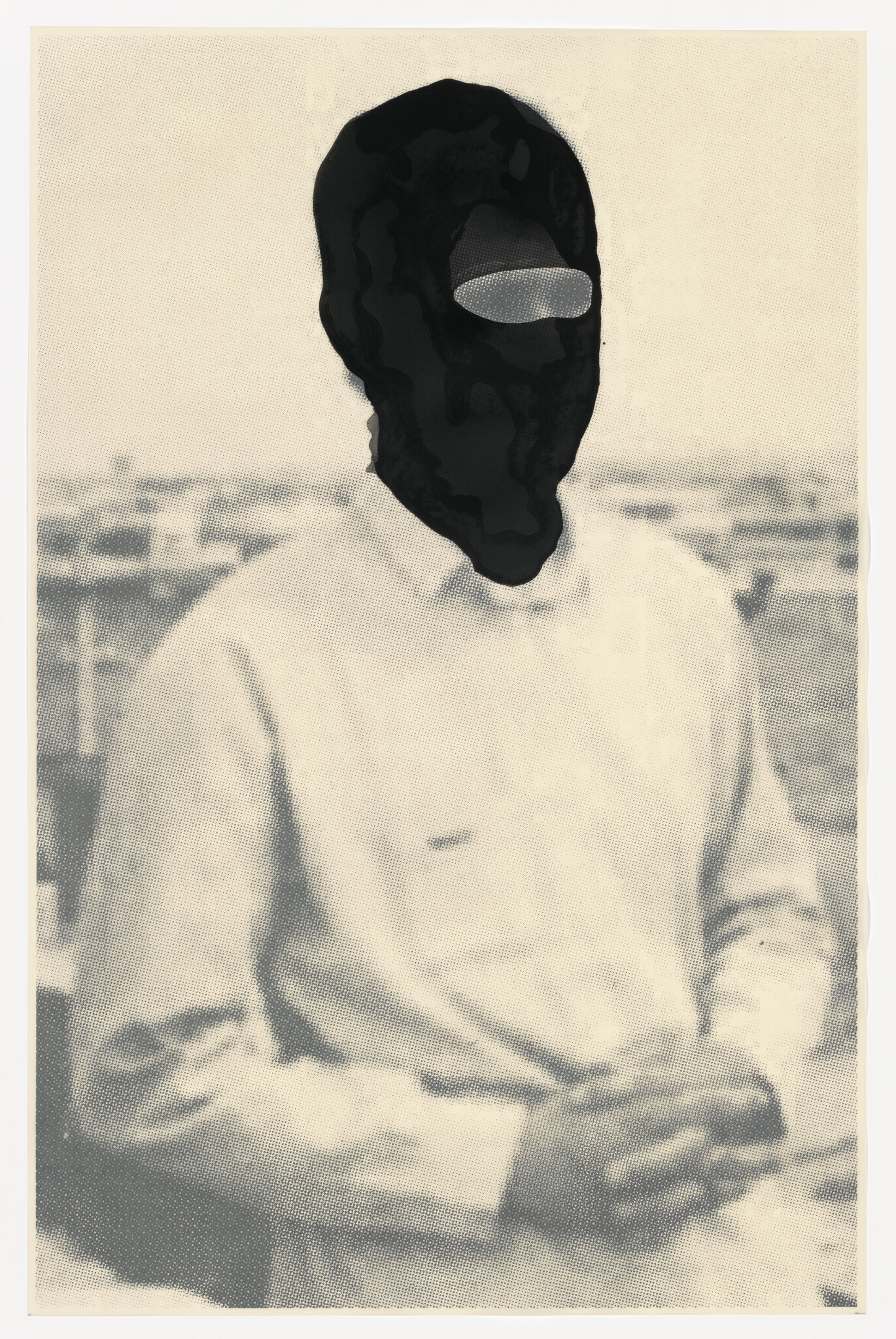 A person wearing a black balaclava sits with hands folded, shoulders and rooftop background visible.