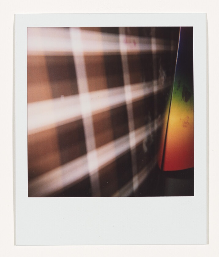 Blurred plaid pattern beside a colorful gradient lamp creating soft light and shadows.