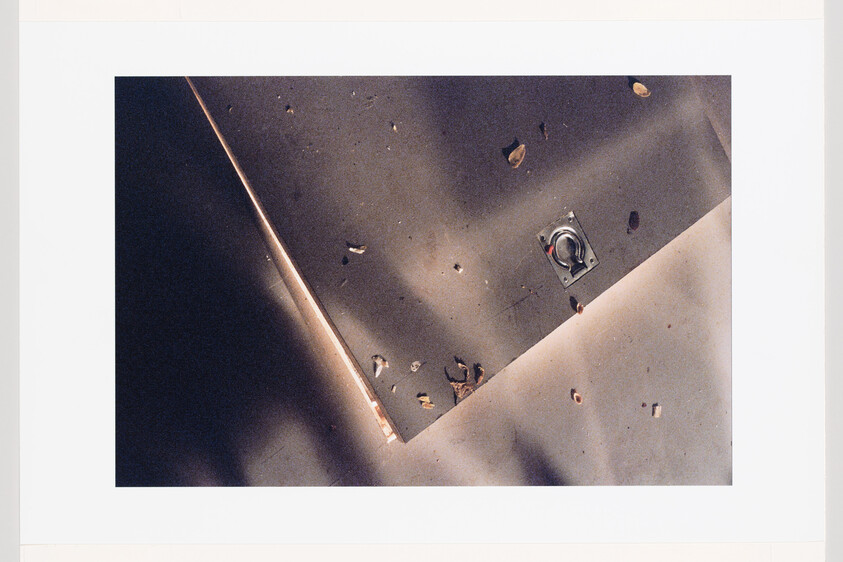 Two drywall sheets overlap on a floor, revealing a recessed electrical box and scattered wood debris.