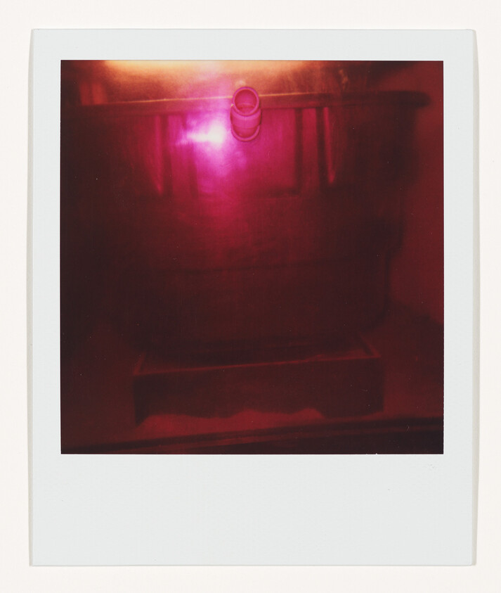 Large plastic bin with a small spout at the top lit by a pinkish-red light.