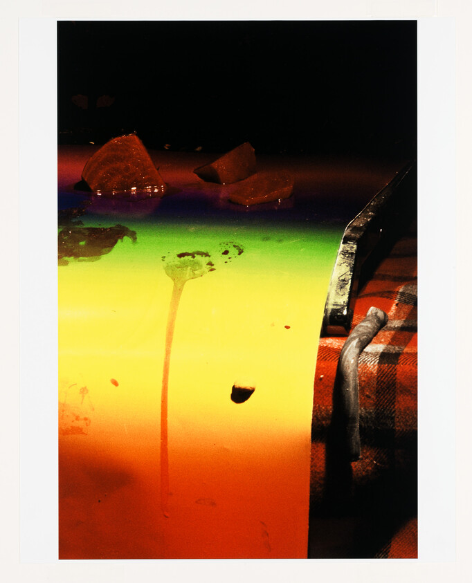 A knife resting on a plaid cloth beside a multicolored surface with broken glass pieces.