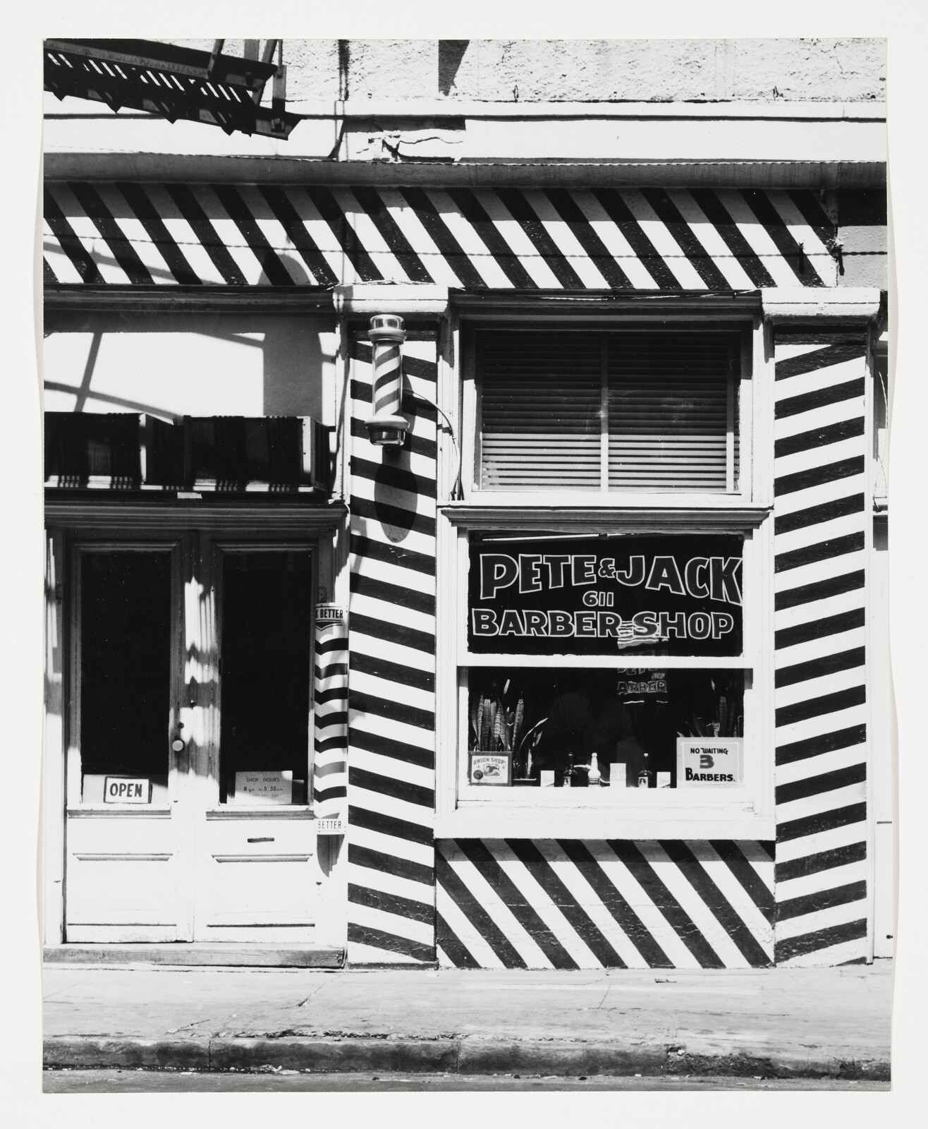 Black-and-white striped storefront of Pete & Jack barber shop with a barber pole and open sign.